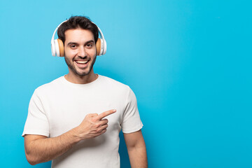 young handsome man looking excited and surprised pointing to the side and upwards to copy space
