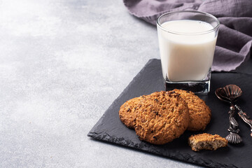 Homemade cookies cereals oats and a glass of milk on the grey concrete table. Copy space.