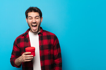 young handsome man shouting aggressively, looking very angry, frustrated, outraged or annoyed,...