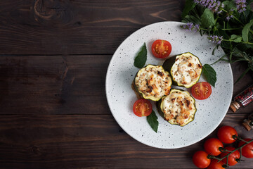 Baked stuffed zucchini columns with minced chicken and vegetables on a plate. Dark wooden background. Copy space.