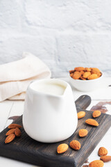 Almond milk in ceramic milk jug on a gray background. Copy space.