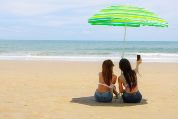 Fototapeta na wymiar Two Asian relaxing girl wear swimsuit on the beach.summer vacation concept