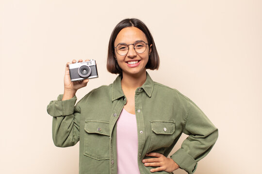 young latin woman smiling happily with a hand on hip and confident, positive, proud and friendly attitude