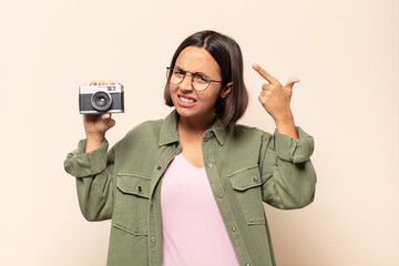 young latin woman feeling confused and puzzled, showing you are insane, crazy or out of your mind