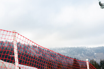 Close-up of  red plastic fence for ski slopes against  mountains