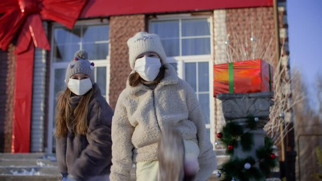 Girls in medical face masks dancing RnB dance outdoors at christmastime. Teenage girls in protective masks having fun together and dancing outdoors while celebrating xmas