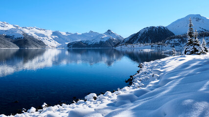Turquoise blue alpine lake with fresh snow on shoreline by snow covered mountains. Garibaldi Lake near Whistler. British Columbia. Canada © aquamarine4