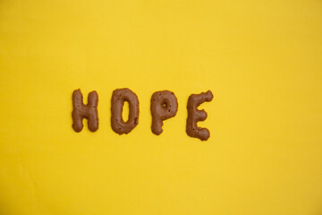 Word Hope arranged from homemade chocolate cookie  alphabet on yellow table