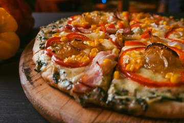 top view Traditional Italian pizza with bacon, paprika, caramelized onions and corn on a black rustic wood background. Top view of hot pizza. restaurant blur background