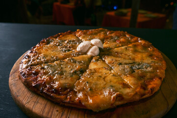 top view Traditional crispy Italian four cheese pizza on a rustic black wood background. Top view of hot pizza. restaurant blur background