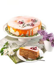food photography of homemade honey cake with boiled condensed milk side view covered with sea ​​buckthorn cream, orange glaze decorated red berries and rosemary on white background isolated close up