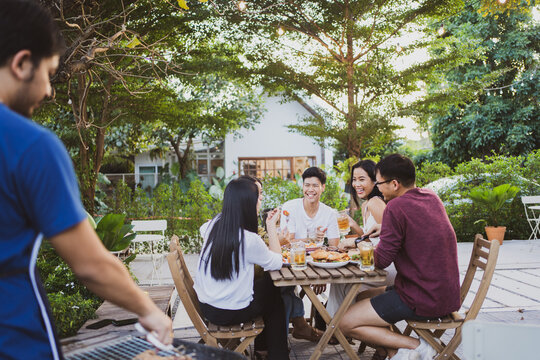 Group Holiday Party Of Asian People Eating Dinner And Drinking Beer At Home