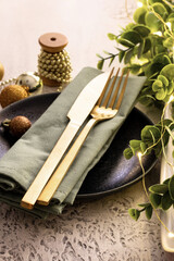 Fototapeta na wymiar Table setting with ceramic plate, gold cutlery , and eucalypt brunch for Merry Christmas and Happy New Year celebration .Beautiful festive dinner tableware.Close up