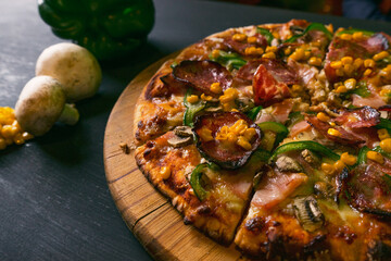 Delicious Italian pizza slice with salami near vegetables on black background