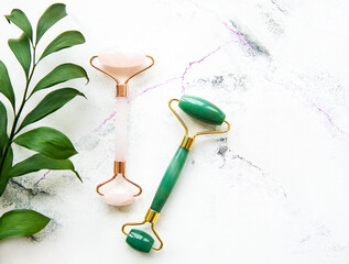 Face massage jade roller  on white marble background