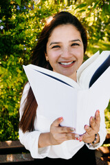 Fototapeta premium Woman with cute freckles smiling and hiding her face with a book