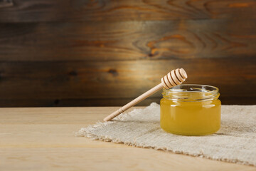 jar of honey is on wooden background in rustic style