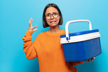 young latin woman screaming with hands up in the air, feeling furious, frustrated, stressed and...