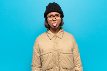 young latin woman feeling disgusted and irritated, sticking tongue out, disliking something nasty...