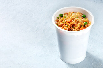 Instant noodles with vegetables in a plastic cup with copy space