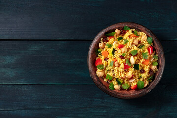 Couscous with vegetables in a tajine, shot from the top on a dark blue wooden background with copy space