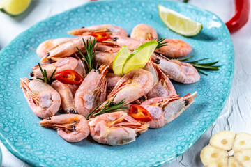fresh boiled shrimp served with lime, rosemary, chili on a blue plate, Seafood. Food recipe background. Close up