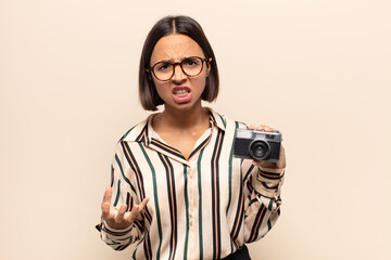 young latin woman looking angry, annoyed and frustrated screaming wtf or what’s wrong with you