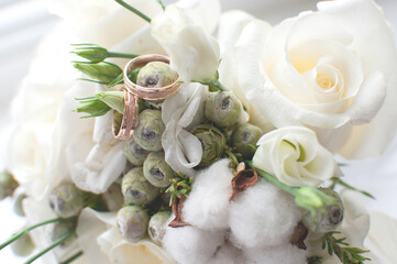 Bouquet with white roses, cotton and rings on a light background