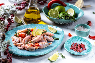 Red boiled shrimps with lime, rosemary, chili on a blue plate on a light background, top view
