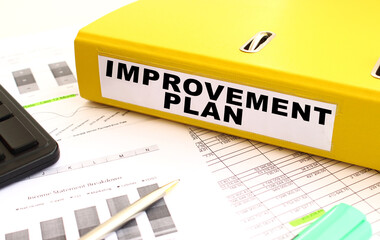 A yellow folder with documents labeled IMPROVEMENT PLAN lies on the office desk.