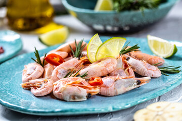 boiled tails of king shrimps served with lime, rosemary, chili on a blue plate, Seafood. Food recipe background. Close up
