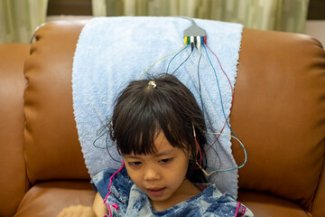 A little girl is doing a neurofeedback exam. Making EEG electrodes.