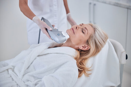 Beautiful adult blonde lady with close eyes spending time in dermatological clinic