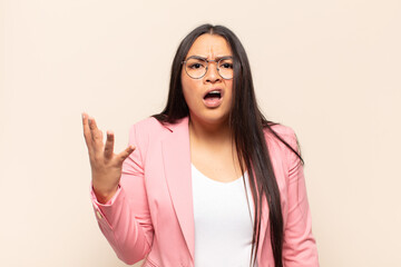 young latin woman looking angry, annoyed and frustrated screaming wtf or what’s wrong with you