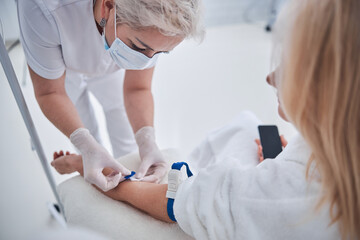 Professional nurse getting treatment vitamin drip for woman in medicine clinic