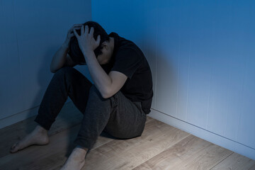暗い部屋で床に座っている男性