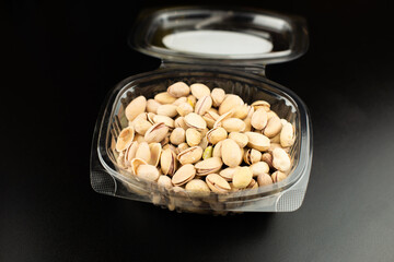 Casserole or box full of pistachios on a black table