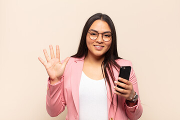 young latin woman smiling and looking friendly, showing number five or fifth with hand forward,...