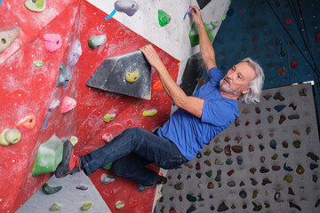 Professional senior man climbing on an artificial rock climbing wall. Extreme sports concept.