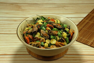 Fried and stirred spicy mussel meat with cutting baby corn, chilly and basil in the bowl. Famous traditional seafood menu in Asia restaurant. 