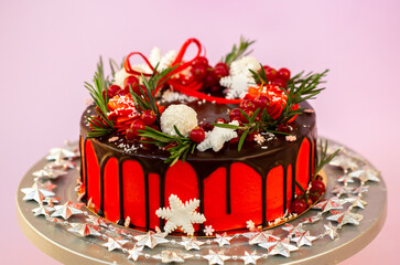 New Year's festive Christmas cake on a stand on a pink background. Christmas sweets decorated with New Year's decor and berries.