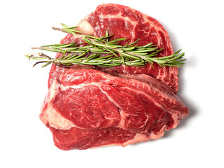 Fresh raw rib eye steak with green rosemary leafs on white isolated surface. Meat industry product. Premium tender meat cut.