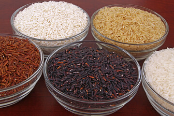 Assortment of rice in glass bowls close up - white, brown, red and black rice.