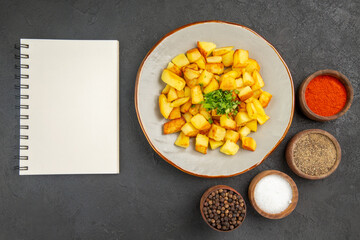 top view tasty fried potatoes inside plate with seasonings on a dark background color oil kitchen dinner food photo