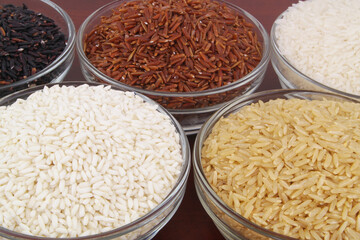 Assortment of rice in bowls close up - white, brown, red and black rice.