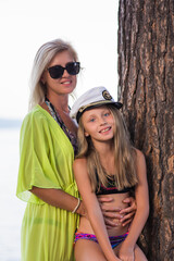 Mother and daughter spend time together in the lake, cuddling tightly and affectionately on a bright summer sunny day outdoors.