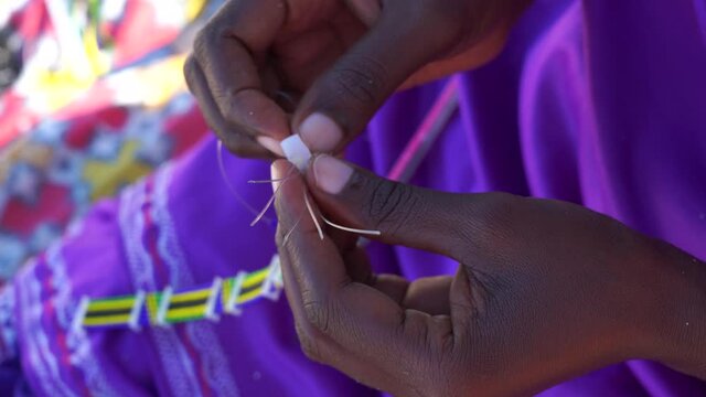 Making of handmade jewellery. Masai african women hands, top view, close up. Island of Zanzibar, Tanzania, East Africa