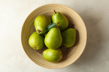 Bowl with green pears on white textured background