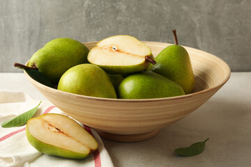 Bowl with green pears and kitchen towel on white textured background