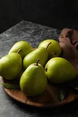 Wooden tray with green pears on black smokey background